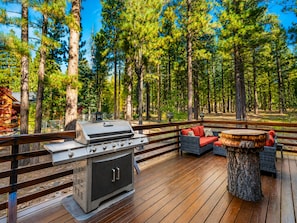 An outdoor deck with a grill, seating area, and a wooden table.