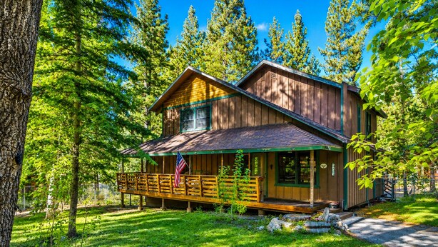 A cabin with a porch, surrounded by trees.