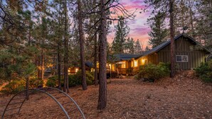 A rustic cabin surrounded by tall pine trees with a wooden exterior and a porch. - Big Bear Villa - Walk to Lake & Village, Hot Tub, Jet Tub, Outdoor Shower (Big Bear Lake)