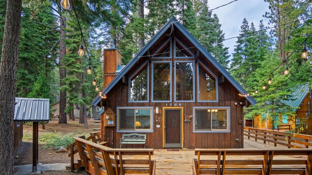 A wooden cabin with a steeply pitched roof, large windows, and a deck with wooden railings. - Inviting and Modern Home in Sunnyside Walk to Lake, Access to Tahoe Park HOA.  By Tahoe Time VR (Tahoe City)