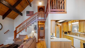A spacious living area with a wooden staircase, a kitchen with wooden cabinets, and a view of the upper floor. - Inviting and Modern Home in Sunnyside Walk to Lake, Access to Tahoe Park HOA.  By Tahoe Time VR (Tahoe City)