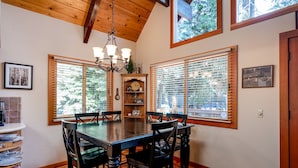 A dining room with a wooden table and chairs, large windows, and a chandelier. - Inviting and Modern Home in Sunnyside Walk to Lake, Access to Tahoe Park HOA.  By Tahoe Time VR (Tahoe City)