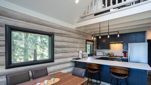A modern kitchen with a large island, bar stools, and a dining area with a wooden table and chairs.