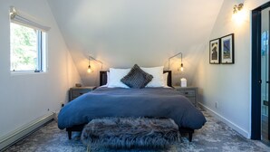 A bedroom with a large bed, two bedside tables, a window, and a door.