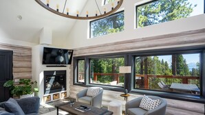 A modern living room with a fireplace, large windows, and a cozy seating area.