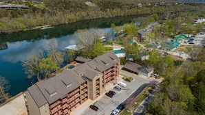 A multi-story hotel with a central courtyard, a parking lot, and a view of a lake.