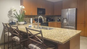 A modern kitchen with granite countertops, stainless steel appliances, and wooden cabinets.