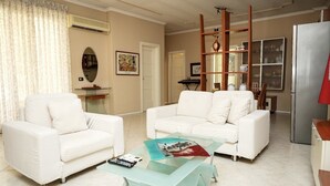 A living room with a white sofa, a glass coffee table, and a wooden bookshelf. - Entire Apartment in the Center of Tirana (Tirana)