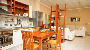 A modern kitchen with a dining area, white cabinetry, and a wooden dining table with chairs. - Entire Apartment in the Center of Tirana (Tirana)