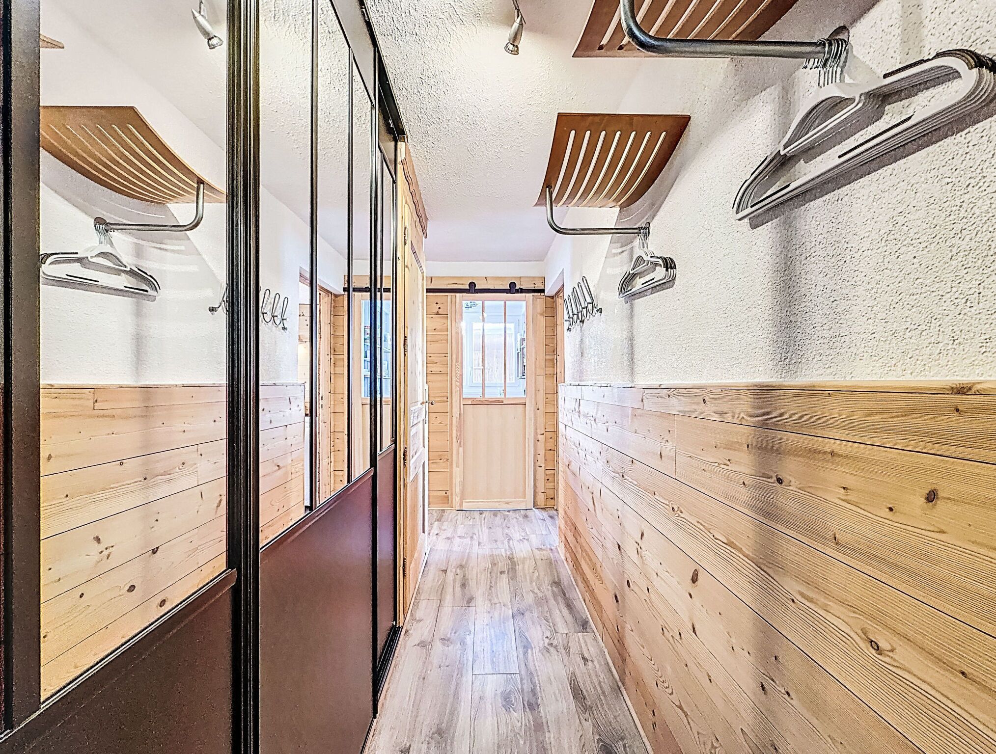 En smal hall med träpanel på väggarna och en glasdörr på vänster sida.