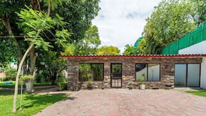 Un edificio de piedra con un patio adoquinado, ventanas grandes y una puerta.