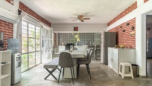 Una cocina con una mesa de comedor, sillas, dispensador de agua y refrigerador.