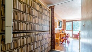 A room with a bookshelf filled with books, a wooden desk with a chair, and a view of the outdoors through a glass door. - Les Moutières B1 et B2 (Val Claret) by Interhome (Tignes)