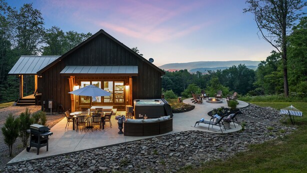 A rustic wooden cabin with a patio area featuring outdoor seating and a hot tub. - ✨ Secluded Luxury w/ Hot Tub, Firepit, Bar + Ultimate Privacy & Views (Ellicottville)