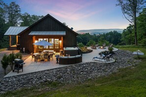 A rustic wooden cabin with a patio area featuring outdoor seating and a hot tub.