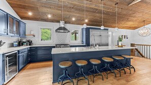 A modern kitchen with a central island, bar stools, and a wooden ceiling. - ✨ Secluded Luxury w/ Hot Tub, Firepit, Bar + Ultimate Privacy & Views (Ellicottville)