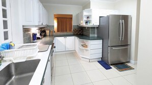 Una cocina moderna con armarios blancos, un refrigerador de acero inoxidable y piso de baldosas.