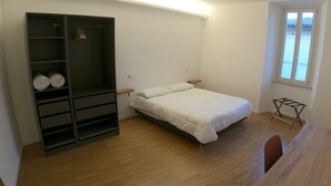 Un dormitorio pequeño y bien iluminado con una cama, un armario y una ventana.