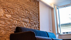 Una habitación con pared de piedra, una ventana y un sofá.
