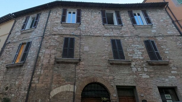 Un edificio de piedra con varias ventanas y una entrada central en arco.