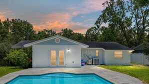 Ein Wohnhaus mit Swimmingpool, Garage und umzäunter Garten.