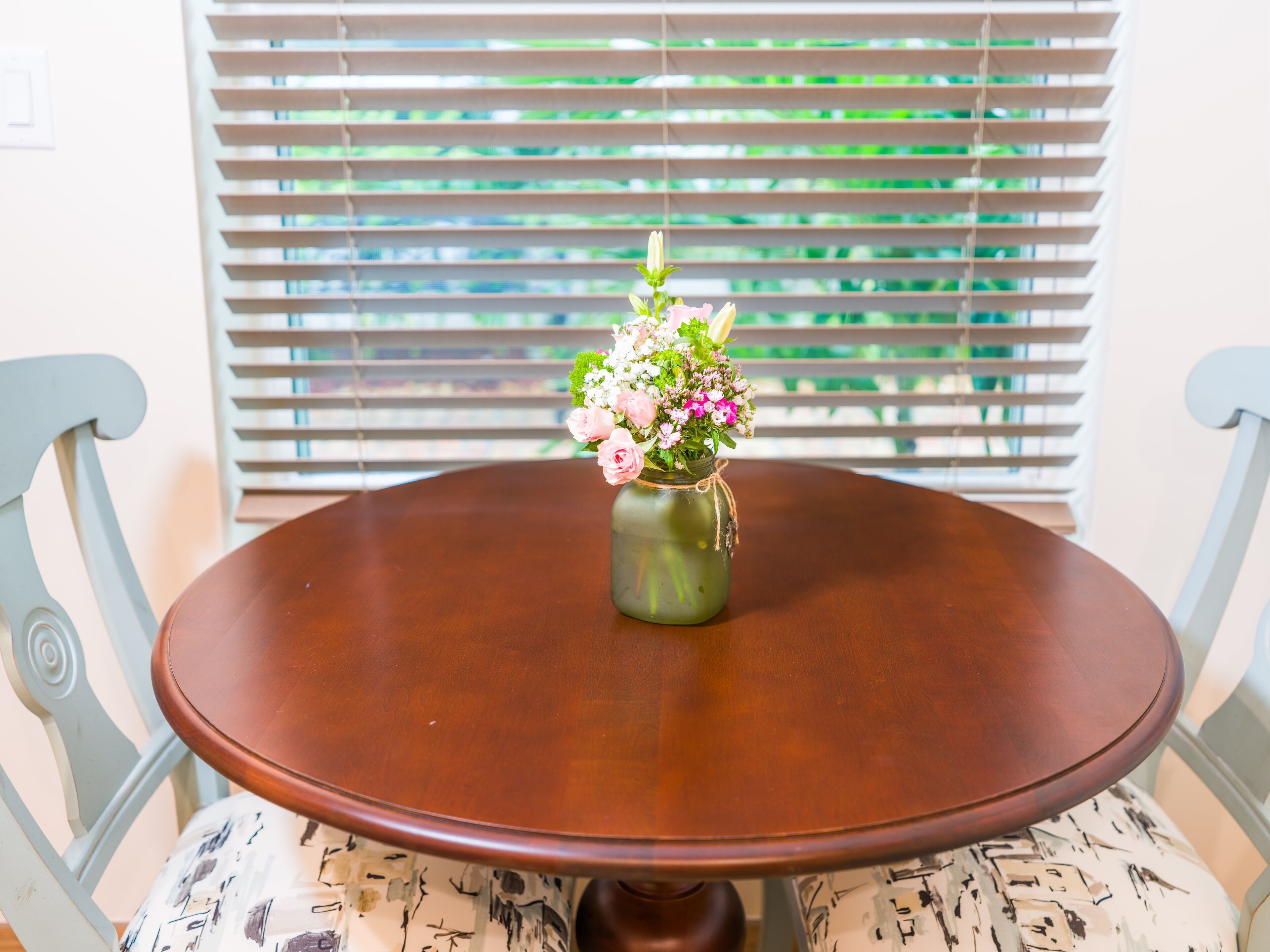 Een ronde houten tafel met een bloemenvaas in het midden.