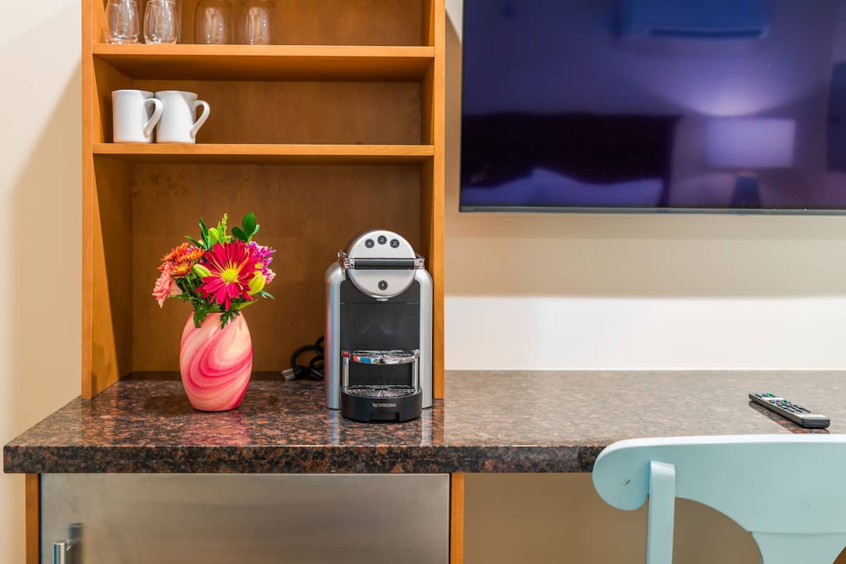 Eine Küchenarbeitsplatte mit einer Kaffeemaschine, einer Blumenvase und einer Fernbedienung.