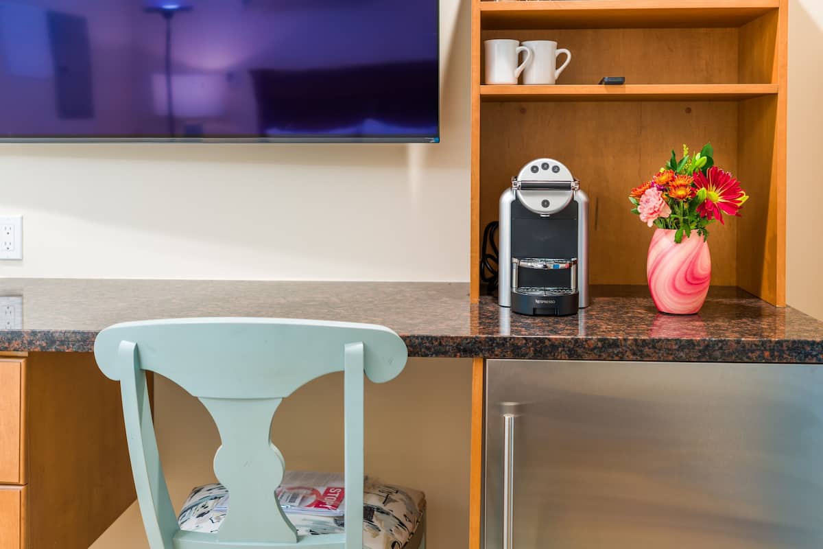 Eine Küche mit Kaffeemaschine, Blumen in einer Vase und einem an der Wand befestigten Fernseher.