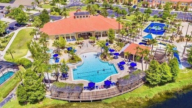 An aerial view of a resort with a central swimming pool, surrounded by palm trees and lounge areas. - Terra verde resort 4brs / 3bth cozy Townhome (Kissimmee)