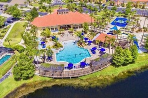 An aerial view of a resort with a central swimming pool, surrounded by palm trees and lounge areas. - Terra verde resort 4brs / 3bth cozy Townhome (Kissimmee)