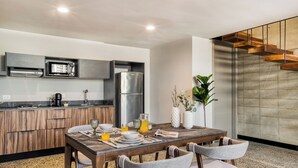 A modern kitchen with wooden cabinets, a stainless steel refrigerator, and a dining area with a wooden table and chairs. - Downtown Loft by ULIV (Tijuana)