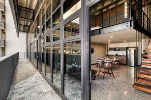 A modern interior with a long hallway, large windows, a dining area, and a kitchen.