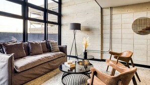 A modern living room with a sofa, coffee table, and chairs, large windows, and a minimalist decor. - Downtown Loft by ULIV (Tijuana)