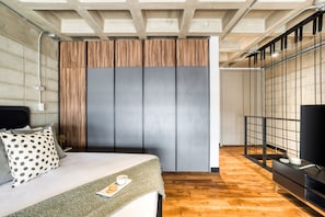 A modern bedroom with a bed, a wooden panel wall, a TV, and a wooden floor.