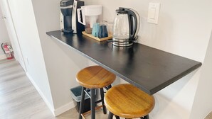 A small kitchen area with a coffee maker, a kettle, and two stools. - 1BR Private Suite · West Vancouver · Landmark View · Prime Location (West Vancouver)