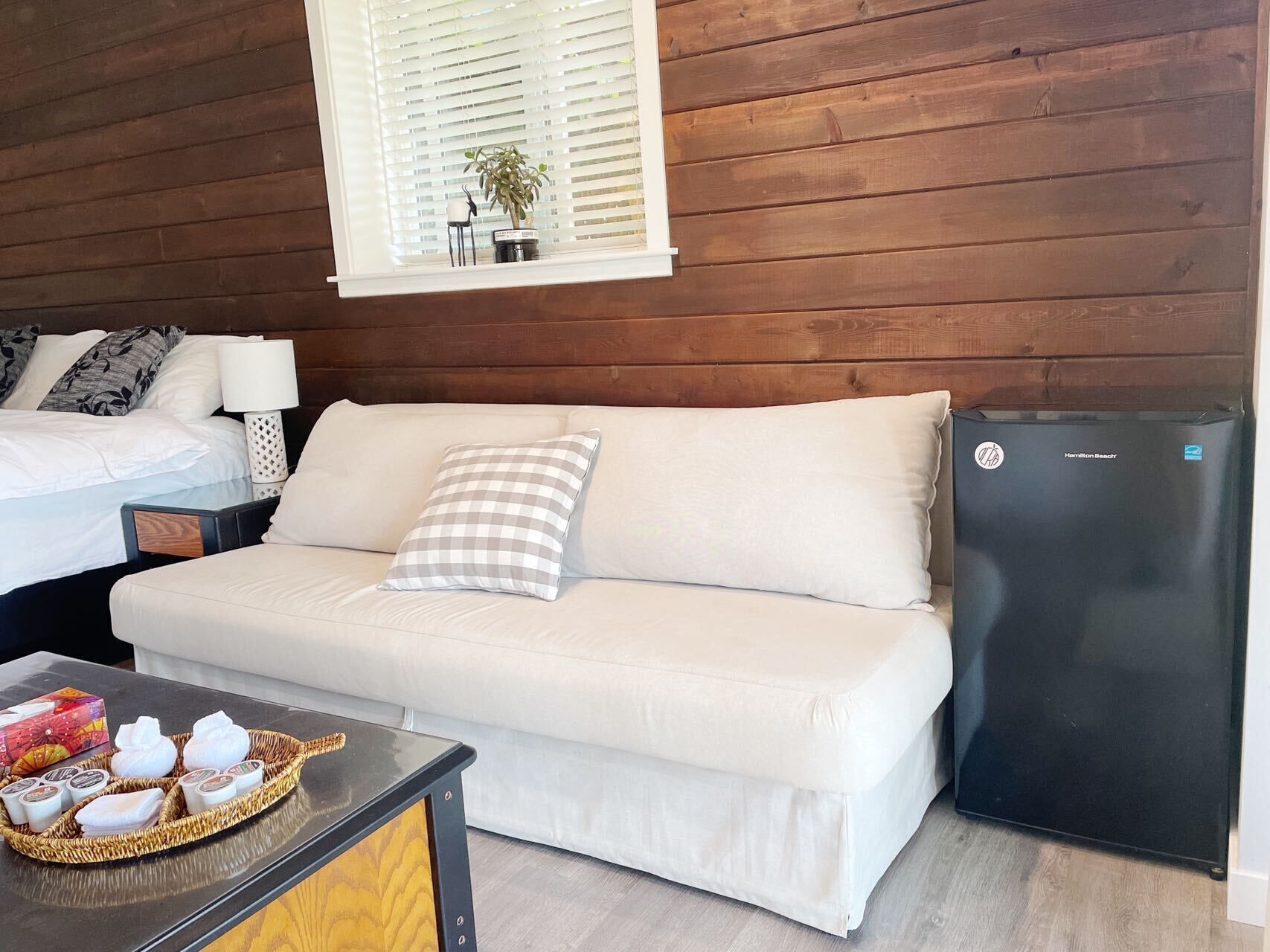 Une pièce confortable avec un canapé blanc, une petite table avec des articles de toilette et un réfrigérateur noir.