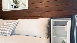 A room with a bed, a window with blinds, and a refrigerator. - 1BR Private Suite · West Vancouver · Landmark View · Prime Location (West Vancouver)