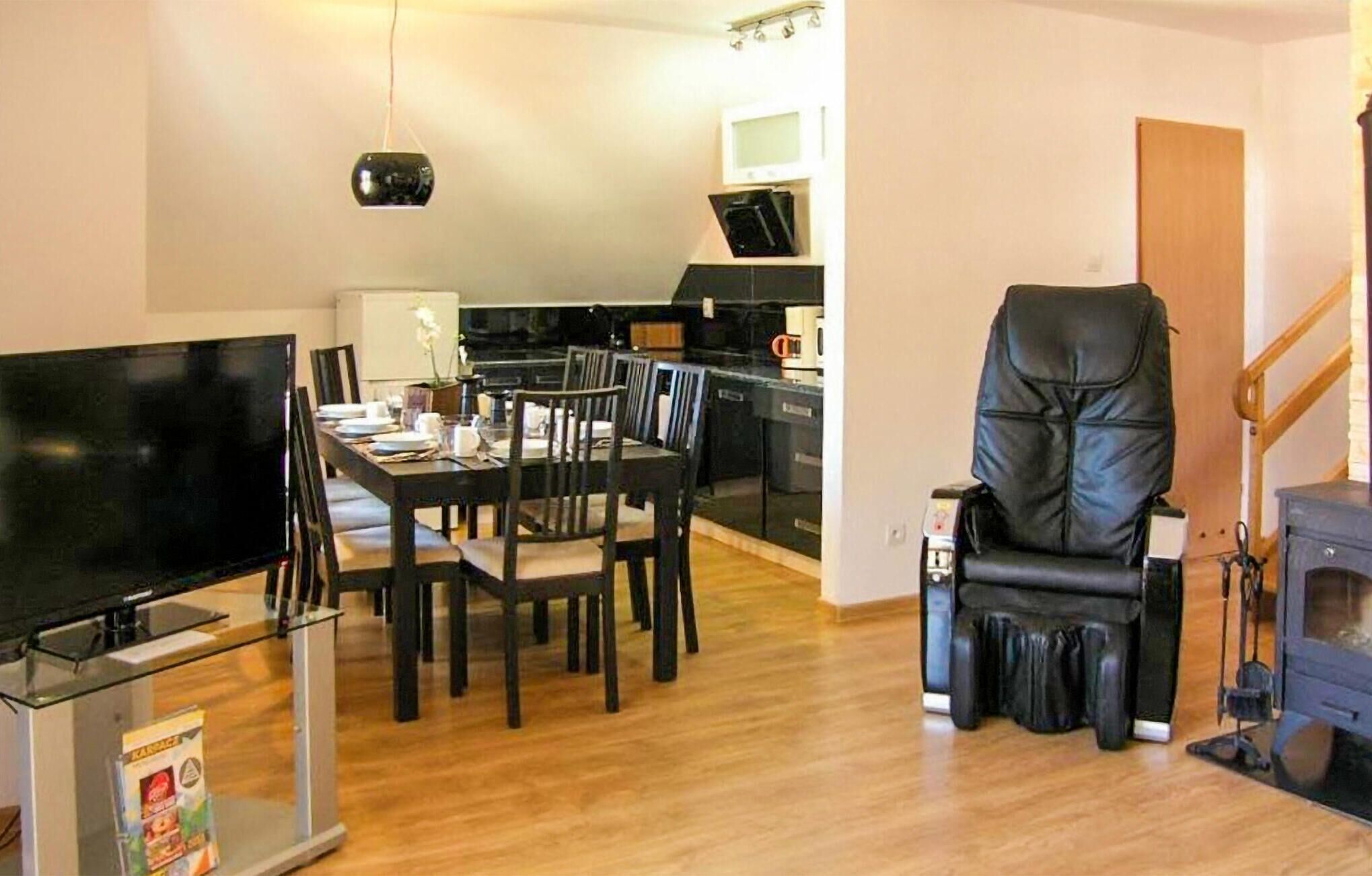 Un espace de vie compact comprenant un coin repas, un téléviseur, un fauteuil en cuir noir et une cheminée.