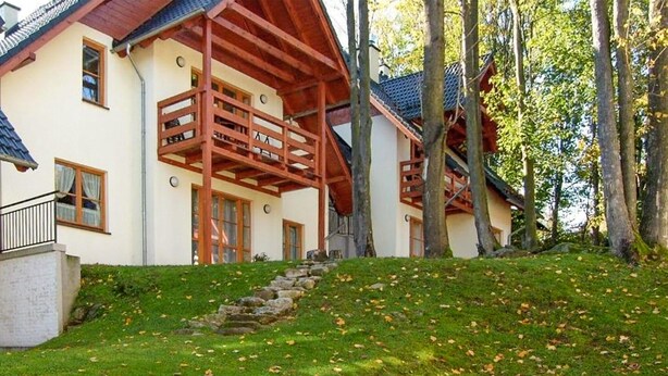 A two-story house with a wooden balcony, a stone staircase, and a lush green lawn. - 3 bedroom pet friendly home in Karpacz (Karpacz)