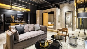 A modern hotel room with a sofa, a dining area, and a bathroom. - Downtown Designer Apartments by ULIV (Tijuana)