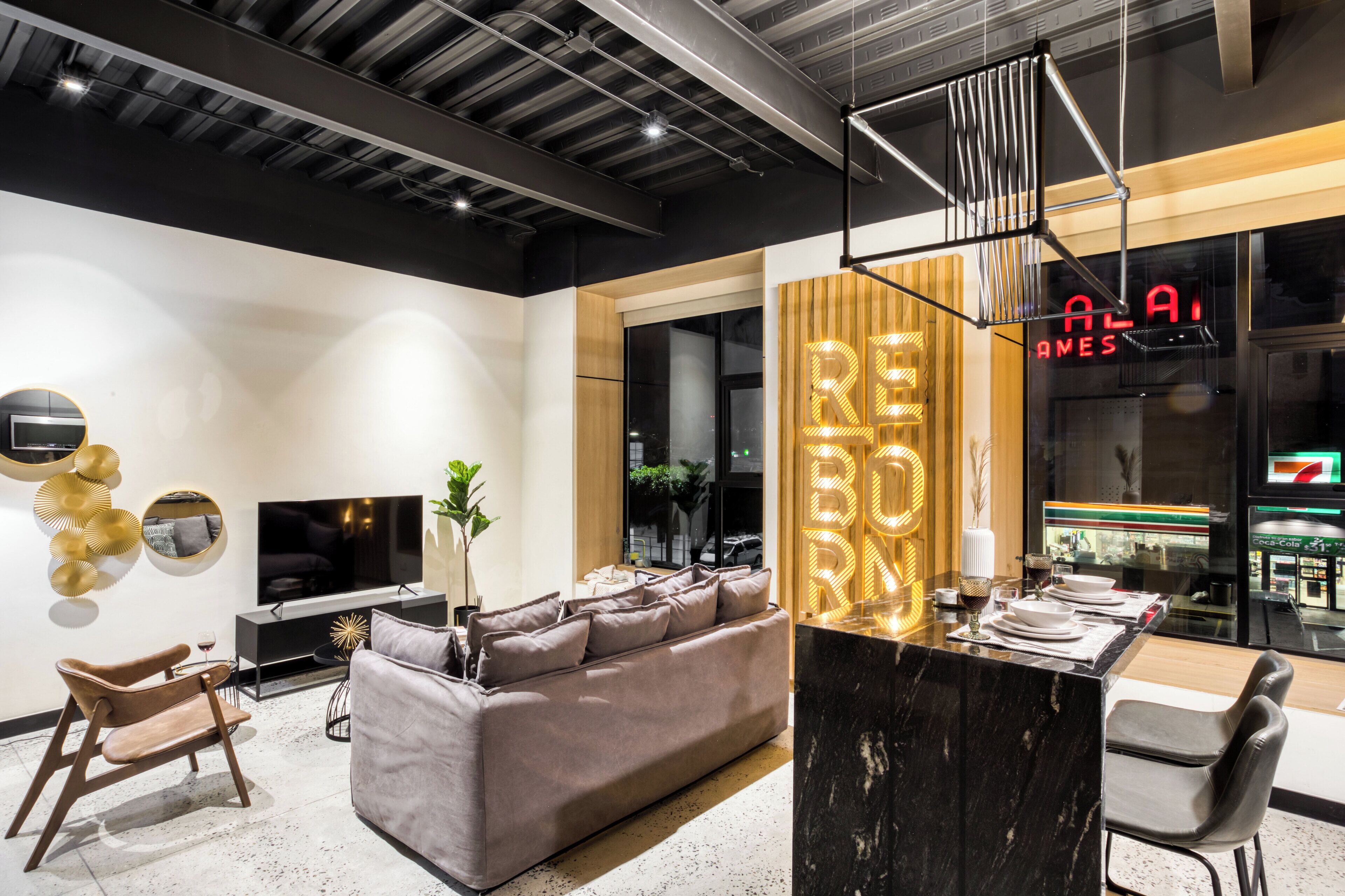 A modern living room with a sofa, a TV, and a dining area with a black marble table.