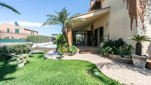 A well-maintained outdoor area with a swimming pool, palm trees, and a patio with outdoor furniture. - Beach front home in Brucoli (Brucoli)