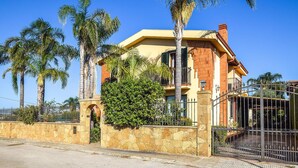A multi-story house with a stone facade, a balcony, and a gated entrance. - Beach front home in Brucoli (Brucoli)