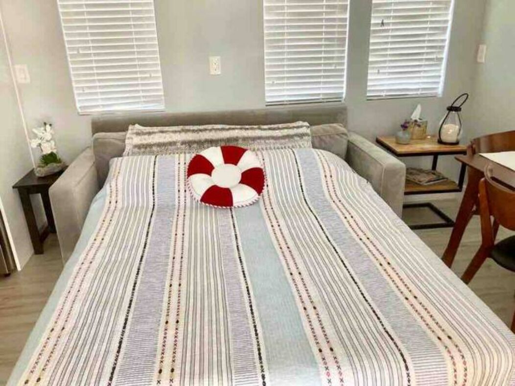A bedroom with a bed, a bedside table, a lamp, and a window with blinds.