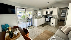 A modern kitchen with white cabinets, a microwave, and a dining area with a table set for two.