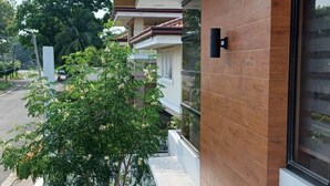 Een modern gebouw met een houten gevel, een balkon en een kleine boom.