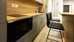 Une cuisine moderne avec un plan de travail en bois, des appareils en acier inoxydable et une chaise noire.