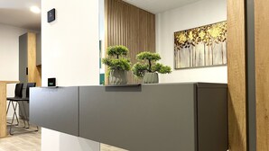 Un comptoir d’accueil agrémenté de deux plantes en pot, un mur recouvert de panneaux en bois et une grande œuvre d’art florale.
