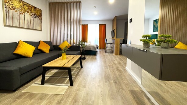 Un salon moderne avec un canapé, une table basse et un meuble pour la télévision, agrémenté de plantes.