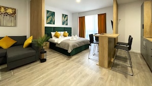 Une chambre d’hôtel moderne équipée d’un lit, d’un bureau, d’une chaise, d’un canapé et d’une plante.